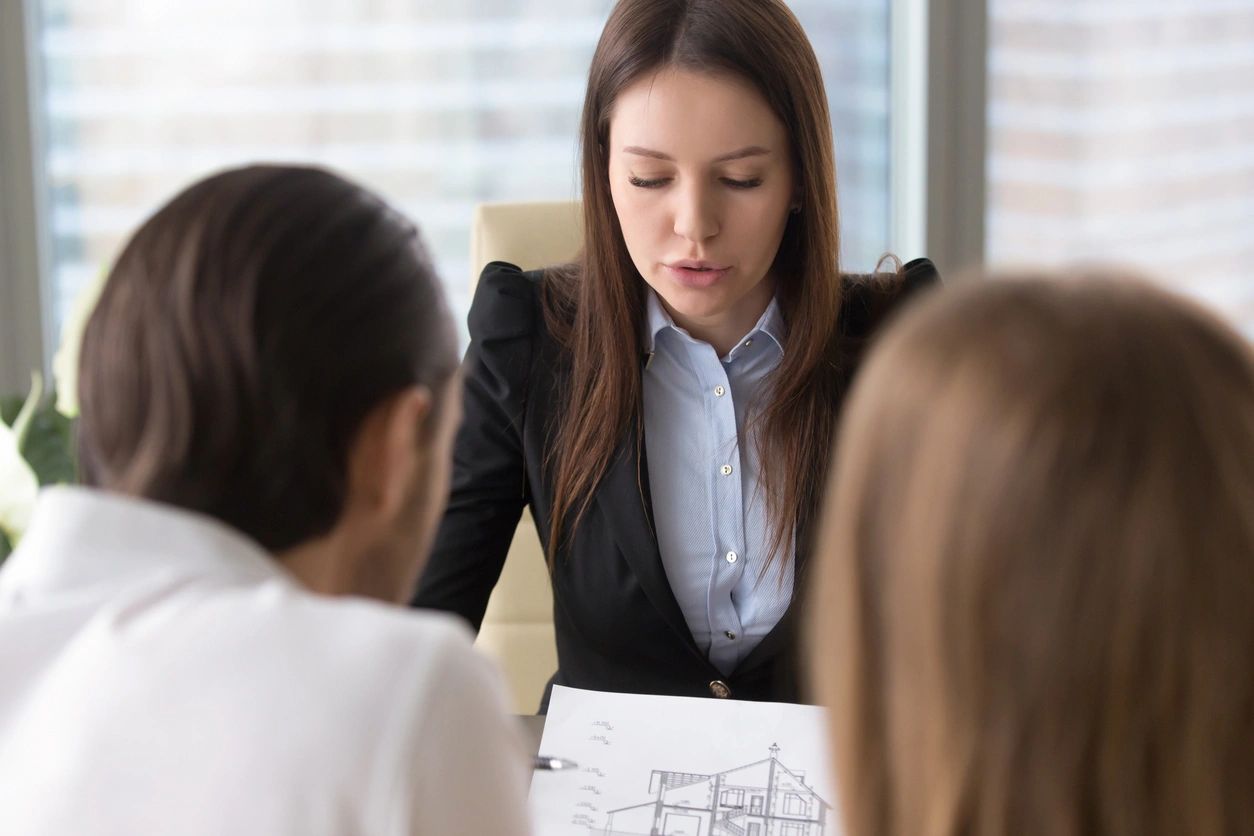 House for sale. Female realtor holding draft with building design of a house presenting it to young couple, professional architects discussing the project, construction interior design planning (House for sale. Female realtor holding draft with buildi